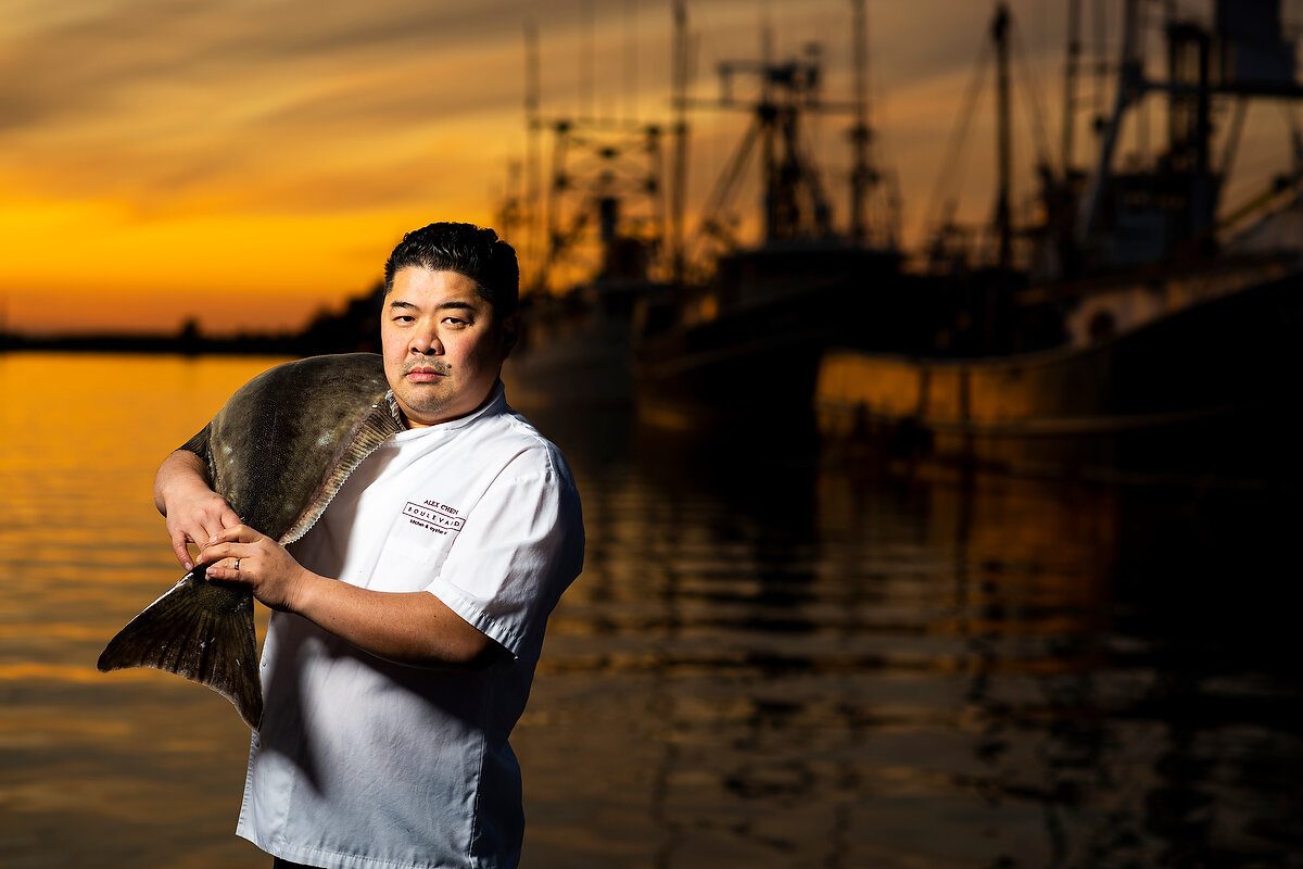 Chef Alex Chen holding a whole flatfish at the docks at sunset