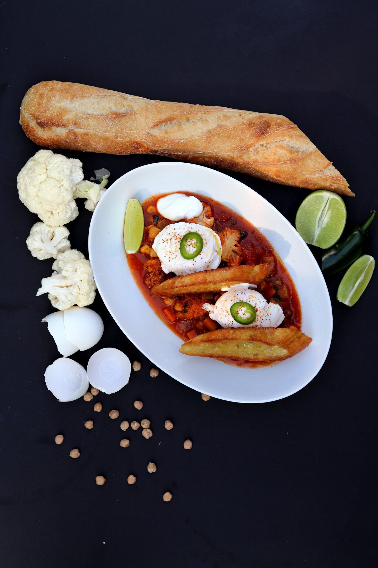 Chickpea chili topped with poached eggs, sour cream, and toasted baguette
