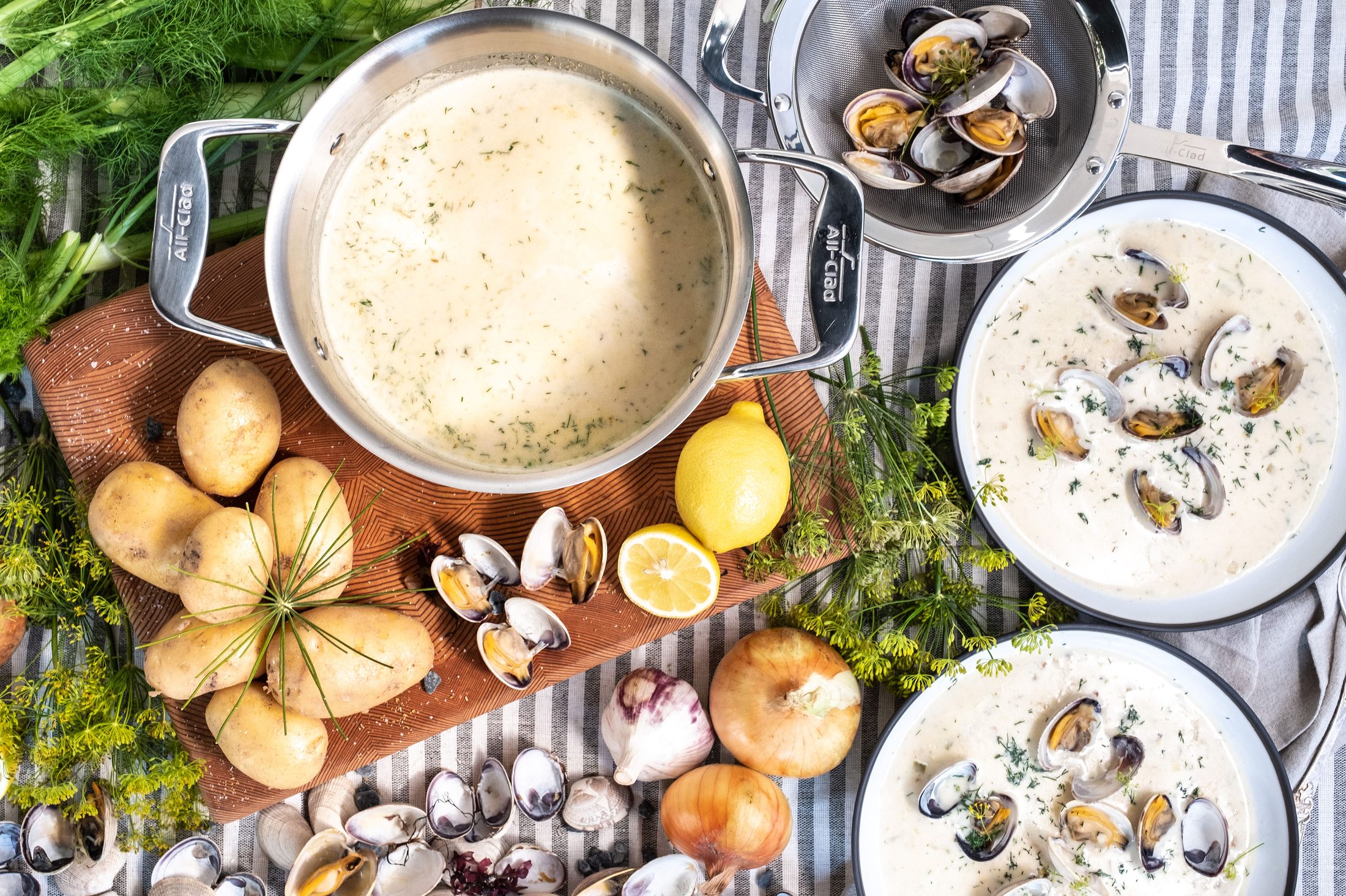 Clam chowder ingredients laid out with an All-Clad pot