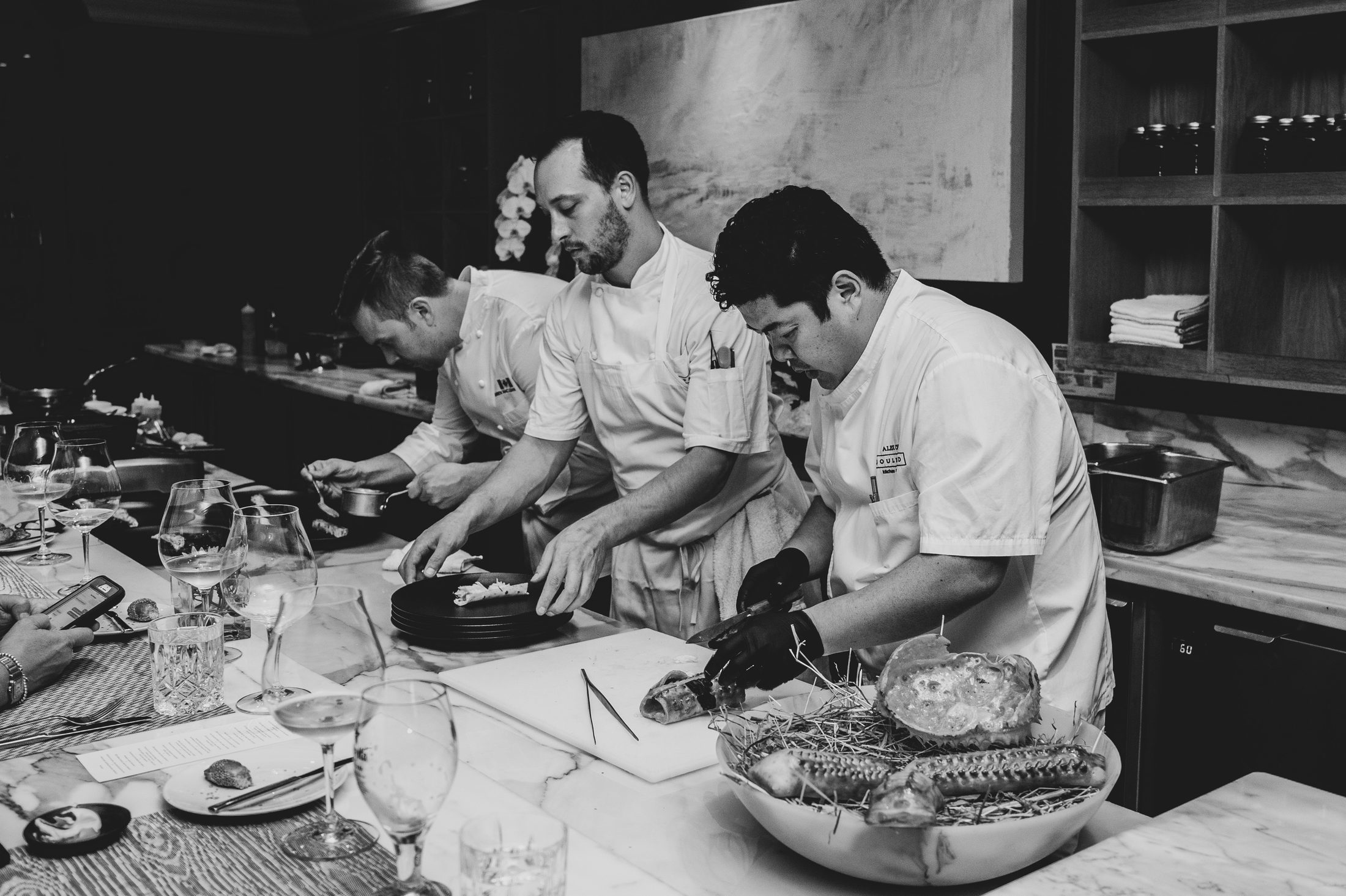Chef Alex Chen and his team plating dishes at the marble counter for TableOne